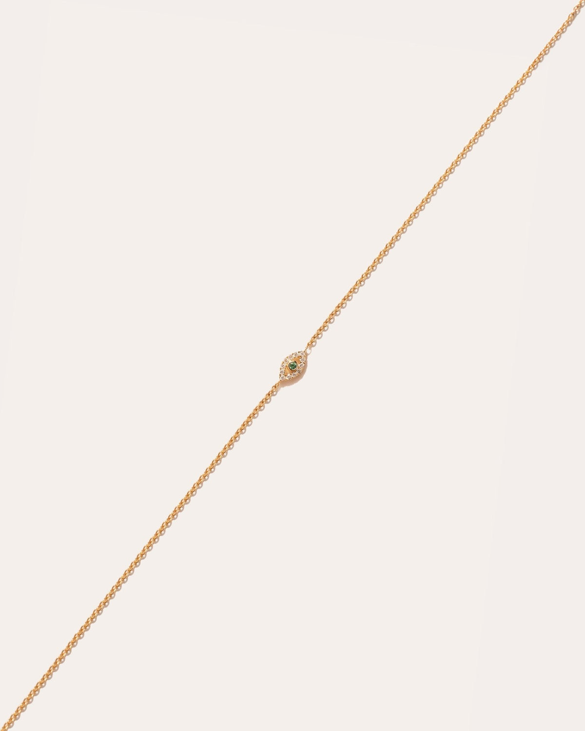 Eirene Eye symbol in 14k yellow gold, set with an emerald and lab grown diamonds, detail view.