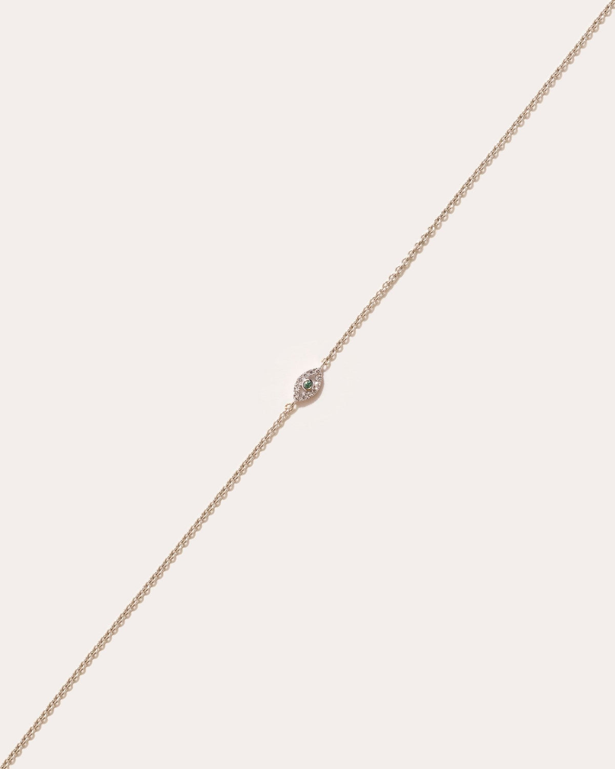 Eirene eye symbol in 14k white gold, set with an emerald and lab grown diamonds, detail view.