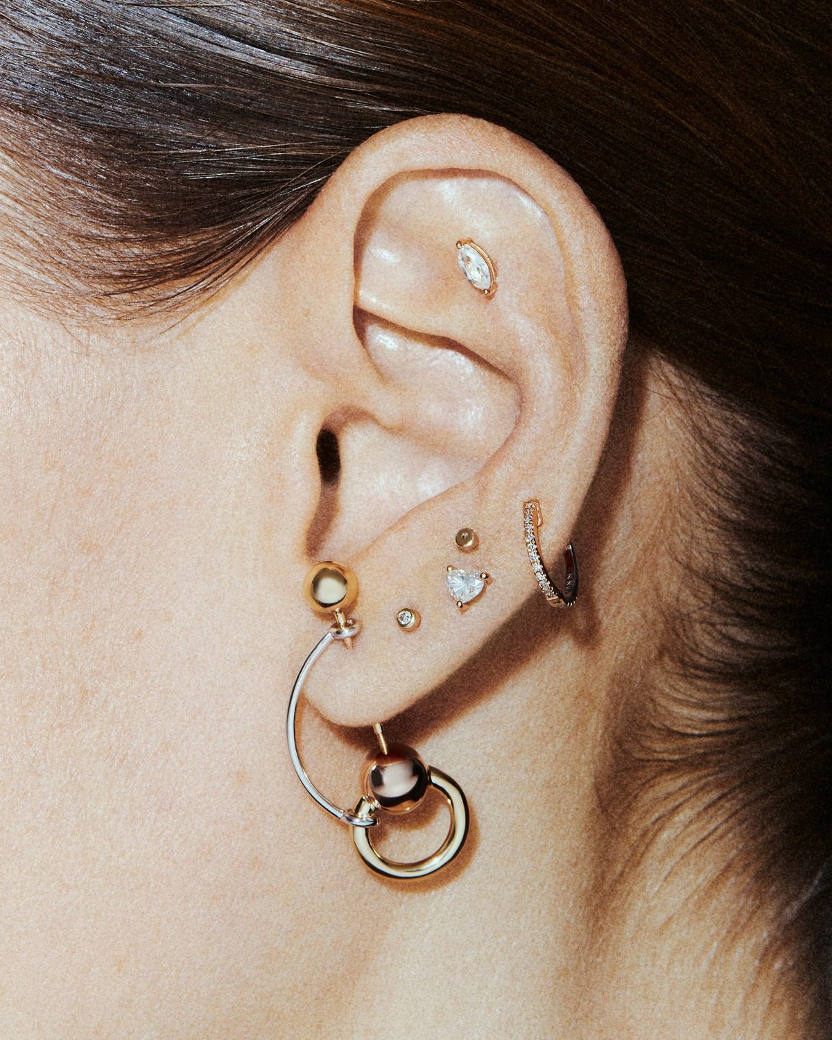 Arch ear pin in 14k yellow gold, shown on the ear.