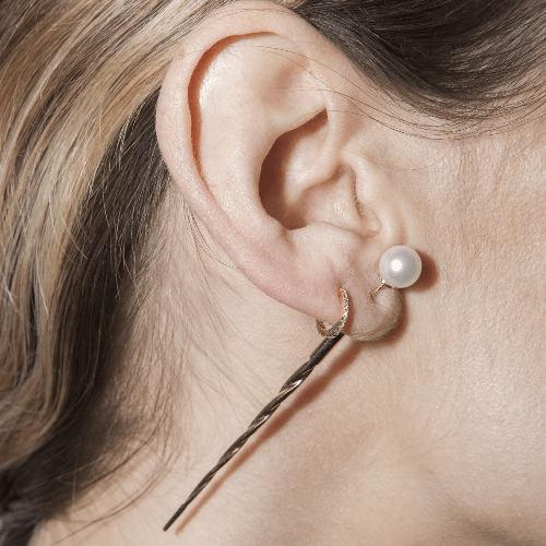 Akoya ear pin in 9k yellow gold, with a pearl, shown on the ear.
